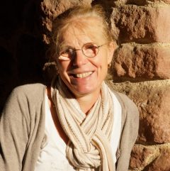 Véronique Stirn adossée à un mur de pierres